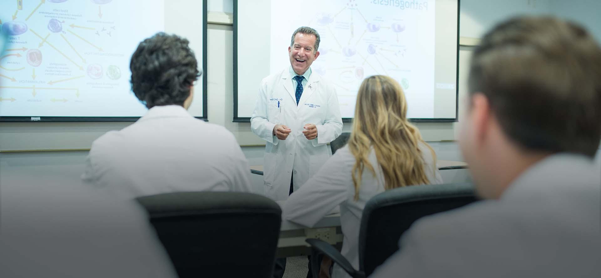 Professor smiling in front of class in white lab coat